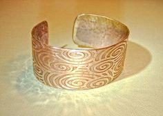 Influenced by Egyptian and Greek jewelry making techniques, this copper cuff bracelet features a flowing Egyptian swirl design that was produced by hammering the flat bracelet form on a steel relief block. I could have used a rolling mill, however the extensive hammering process produces tool marks, an ancient appearance, semi polished surface with irregularities which define handmade, and artistic touches that cannot be replicated with a machine.The 1 inch wide flat bracelet form was sheared fr Artisan Silver Copper Cuff Bracelet, Silver Artisan Cuff Bracelet In Copper, Artisan Silver-colored Copper Cuff Bracelet, Artisan Silver Cuff Bracelet In Copper, Handmade Copper Bracelet, Flat Bracelet, Copper Bracelets, Rolling Mill, Metal Forming