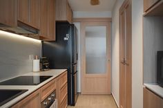 a narrow kitchen with wooden cabinets and black appliances, along with white counter tops on both sides