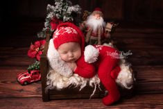 a baby sleeping in a wooden crate with santa clause on it's back and other christmas decorations