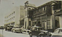 an old black and white photo of cars parked on the street in front of buildings