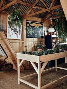 a wooden table with plants on it in a room that has wood walls and beams