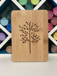 a wooden plaque with a tree on it in front of some colored crayons