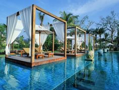 an outdoor swimming pool with cabanas and lounge chairs