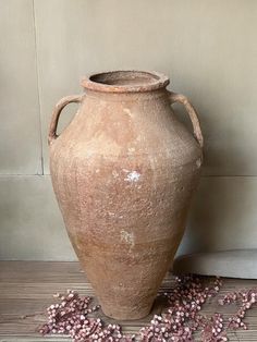 a large brown vase sitting on top of a wooden floor next to a pile of beads