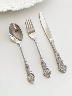 a set of four silverware on a white table