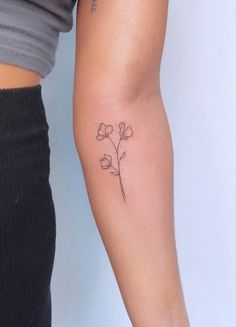 a woman's arm with a small flower tattoo on the left side of her arm