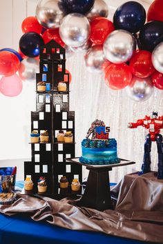 a table topped with cake and cupcakes next to balloons