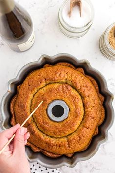 someone holding a toothpick over a cake in a pan with the words use a bamboo skewer or toothpick to poke holes all over the cake bottom