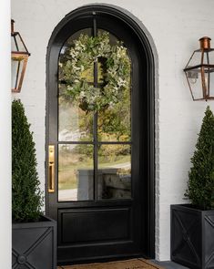 the front door is decorated with wreaths and potted plants, along with two black planters