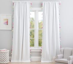 a white curtain with pink and blue pom - poms on it