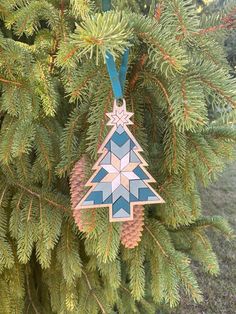 a christmas tree ornament hanging from a pine tree branch with blue and white geometric designs