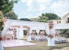 an outdoor wedding setup with white drapes and pink flowers