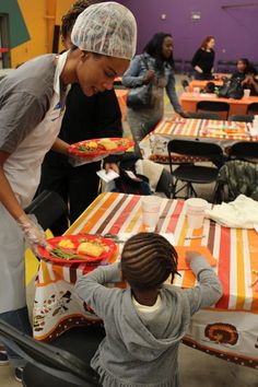 a woman serving food to a child at a table with orange and white striped tables