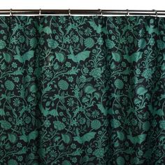 a black and green shower curtain with floral designs on the bottom, in front of a white background