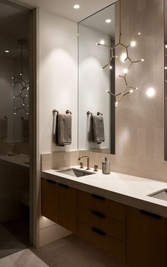 a bathroom with two sinks, mirrors and lights on the wall above them is shown