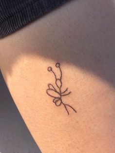 a small tattoo on the back of a woman's leg that has flowers drawn on it