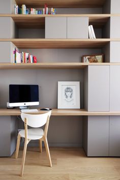 a desk with a computer on top of it in front of a bookshelf