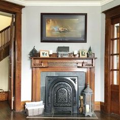 a living room with a fire place next to a painting on the wall and wooden floors