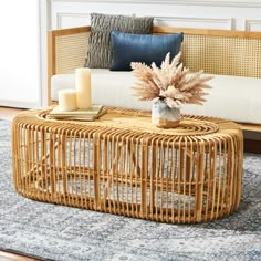 a wicker coffee table sitting on top of a blue rug next to a couch