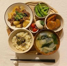 bowls of food are arranged on a wooden tray