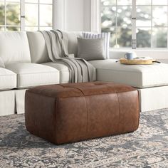 a living room with a couch, ottoman and coffee table in front of the window