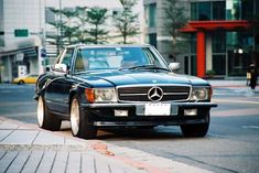 a mercedes benz is parked on the side of the road in front of some buildings