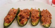 four stuffed green peppers on a white plate