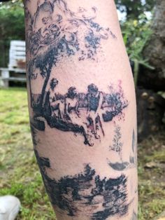 a person with a tattoo on their leg is standing in front of some trees and water