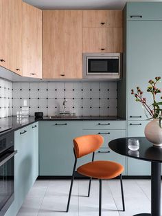 an orange chair sits in the middle of a kitchen with blue cabinets and black countertops