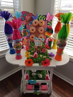 a table topped with lots of colorful vases filled with flowers and donut holes