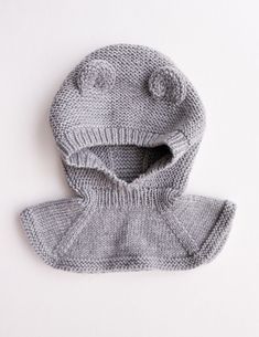 a knitted hat and mitten set on a white surface with the hood up