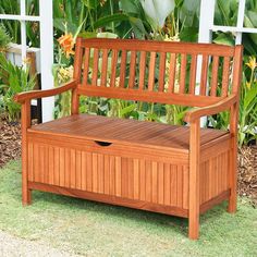 a wooden bench sitting on top of a grass covered field next to flowers and trees