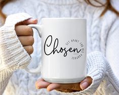 a woman holding a white coffee mug with the word chosen on it in black ink