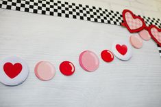 red and white hearts are lined up on a table with black and white checkered wallpaper