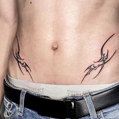 a man's stomach with tattoos on it and his jeans rolled up to the side