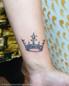 a woman's arm with a small crown tattoo on the left side of her wrist