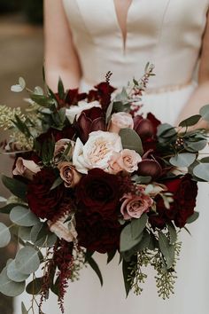 a bride holding a bouquet of flowers and greenery