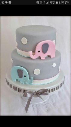 a three tiered cake decorated with elephants and polka dots is on a white tablecloth