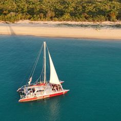 a red and white boat in the ocean with people on it's back end