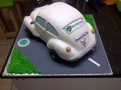 a cake shaped like a vw bug on top of a table with green grass