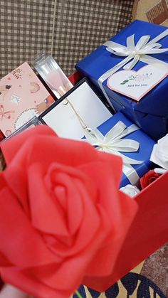 a red rose sitting on top of a blue box filled with gifts