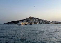 an island in the middle of the ocean with buildings on top and water below it