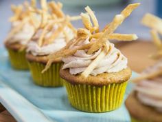 three cupcakes with white frosting and sprinkles sitting on a blue plate