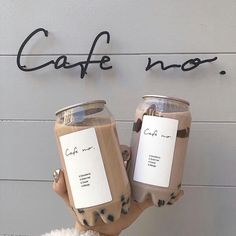 a person holding two cups of coffee in front of a sign that says cafe inc