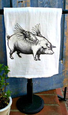 a tea towel with an image of a pig on it hanging from a clothes line