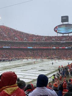 a football stadium filled with fans and players on the field during a snowstorm or blizzard