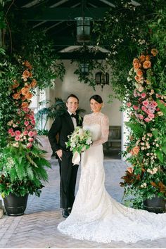 a bride and groom standing under an arch with flowers