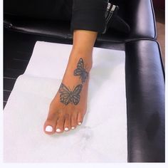 a woman's foot with a butterfly tattoo on her left leg, sitting on a black leather chair