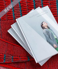 three magazine covers sitting on top of a red table cloth next to a pair of scissors