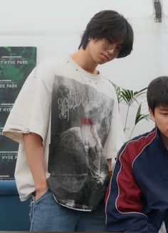 two young men standing next to each other in front of a table with a laptop on it